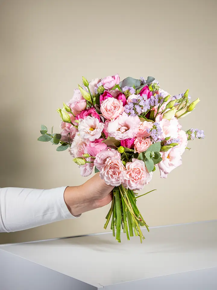 Bouquet rosa pastello di lisianthus garofani statice in mano